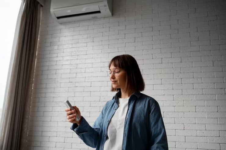 Donna con telecomando climatizzatore