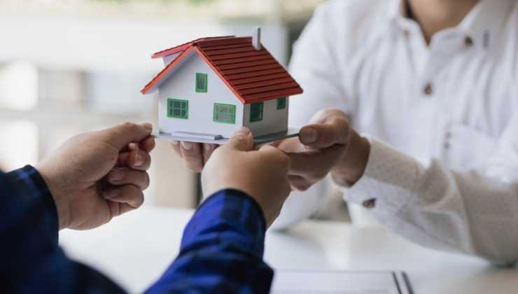 passaggio di modellino casa tra persone