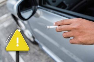 uomo che fuma in auto e segnale di pericolo
